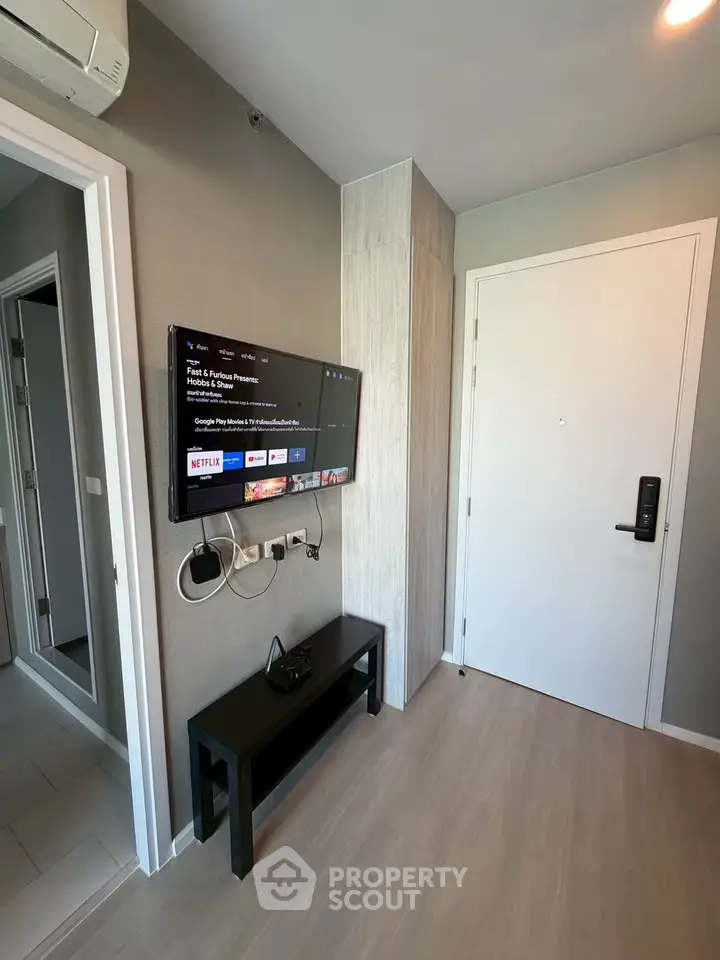 Modern apartment entrance with wall-mounted TV and sleek decor
