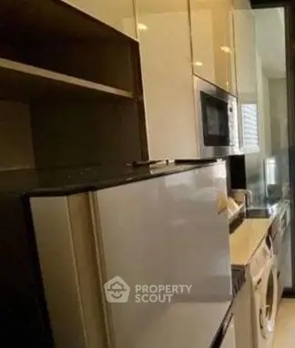 Modern kitchen with sleek appliances including fridge, microwave, and washing machine.