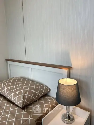 Cozy bedroom corner with stylish lamp and patterned bedding