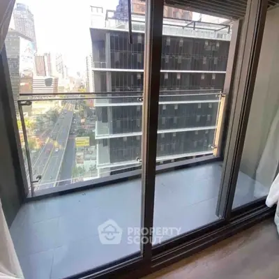Modern balcony with glass railing offering cityscape views from high-rise apartment.