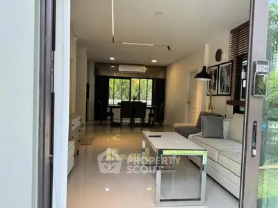 Modern living room with sleek furniture and dining area, featuring large windows and glossy flooring.