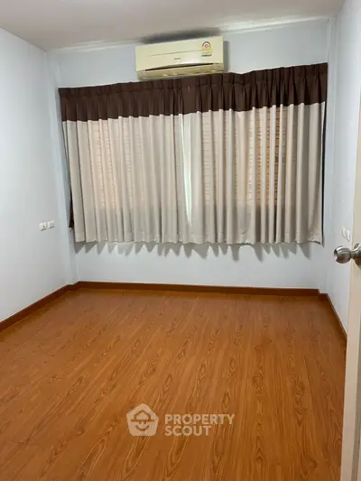 Spacious empty room with wooden flooring and air conditioning unit