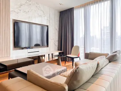 Luxurious modern living room with large TV and elegant furniture, featuring floor-to-ceiling windows.
