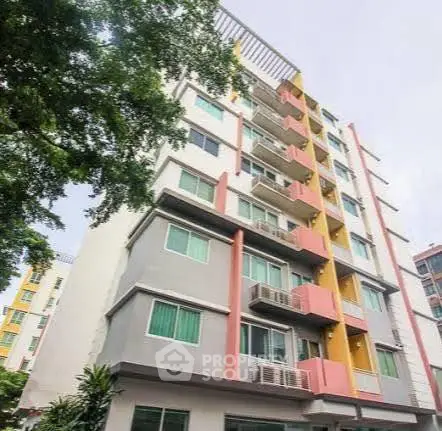 Modern multi-story apartment building with colorful facade and lush greenery.