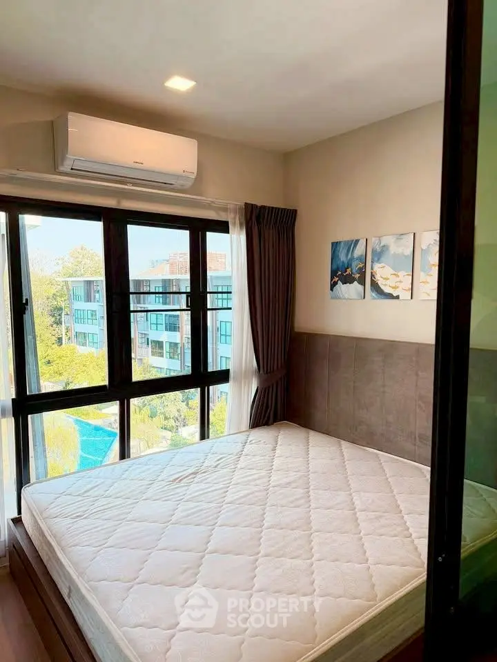 Bright bedroom with large window and scenic view, featuring modern decor and air conditioning.