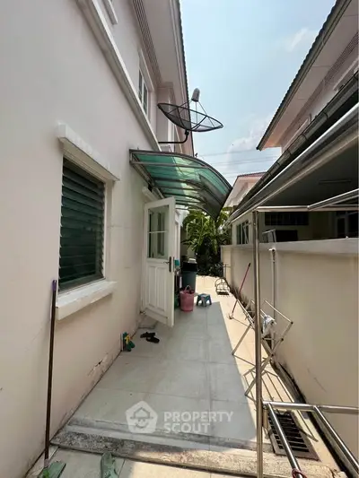 Charming side entrance of a suburban home with a covered walkway and satellite dish.