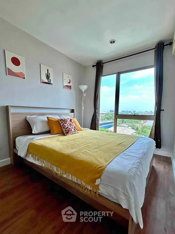 Bright bedroom with large window offering stunning city view, modern decor, and cozy ambiance.
