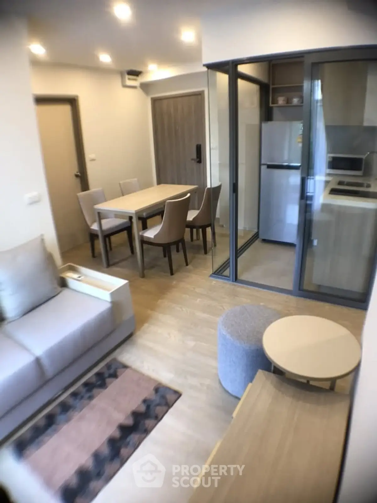 Modern living room with open kitchen and dining area, featuring sleek furniture and contemporary design.