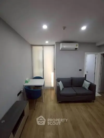 Modern living room with cozy sofa and dining area, featuring sleek wooden flooring and ambient lighting.