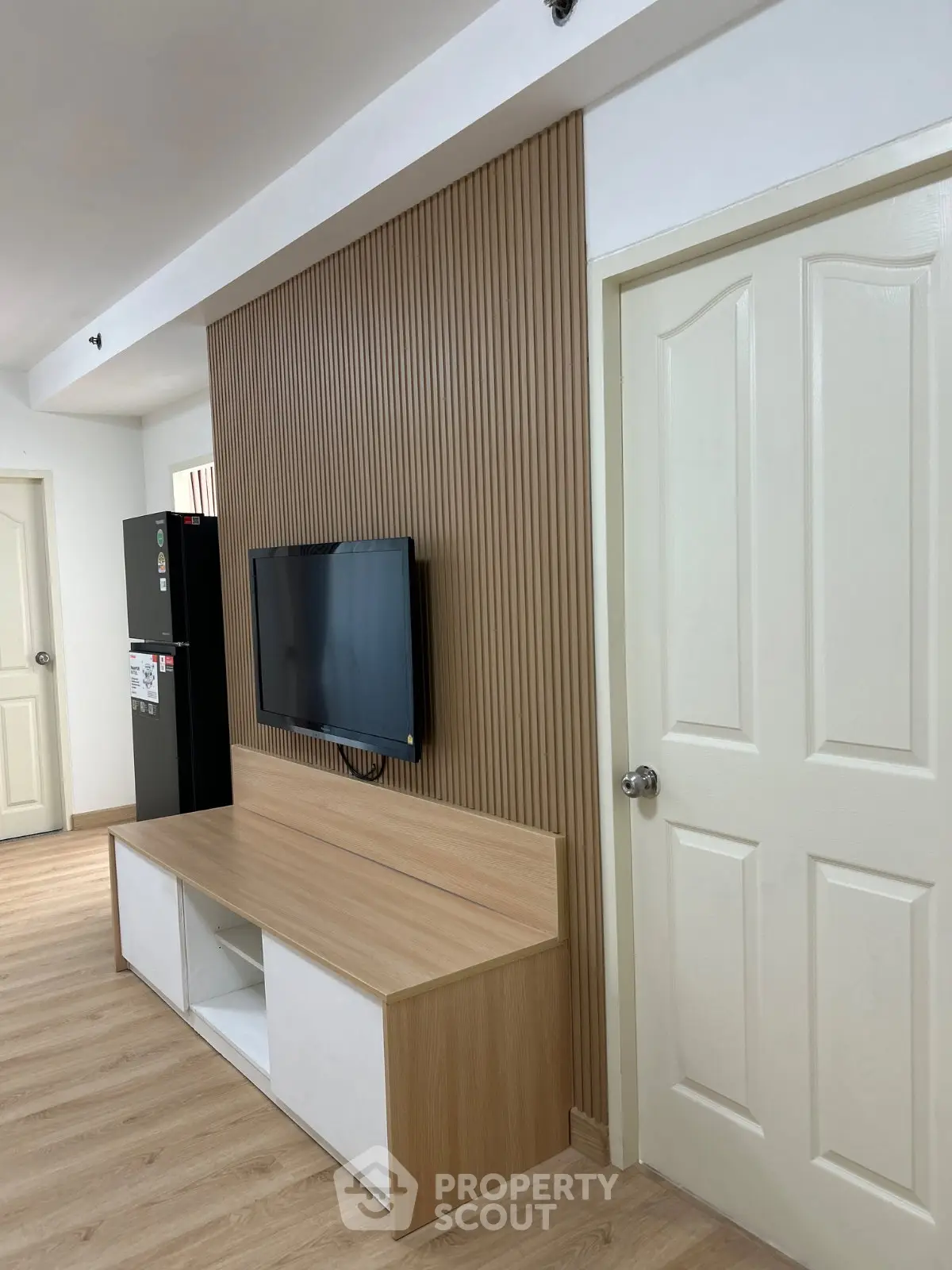 Modern living room with sleek wooden paneling and mounted TV, showcasing minimalist design and elegance.
