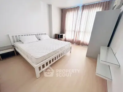 Spacious bedroom with natural light and modern furnishings in a stylish apartment.