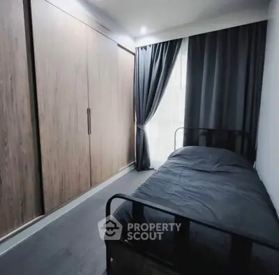 Modern bedroom with sleek design, featuring a single bed and large wooden wardrobe.