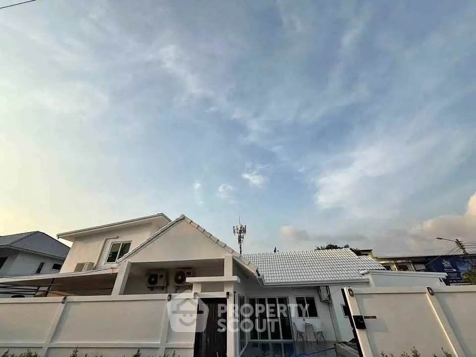 Charming modern house with white facade and tiled roof under a clear blue sky.