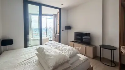 Modern bedroom with city view, featuring a cozy bed, TV, and floor-to-ceiling windows.