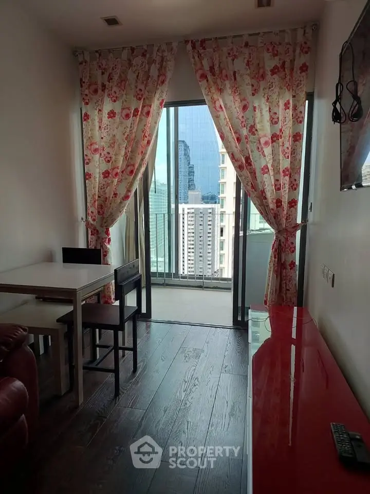 Charming living room with floral curtains and city view from balcony, featuring elegant wooden flooring.