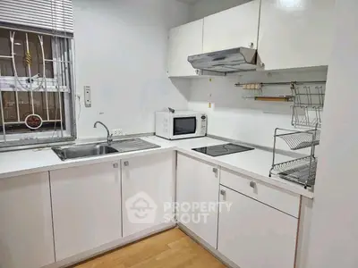 Modern kitchen with sleek white cabinets and built-in appliances, perfect for culinary enthusiasts.
