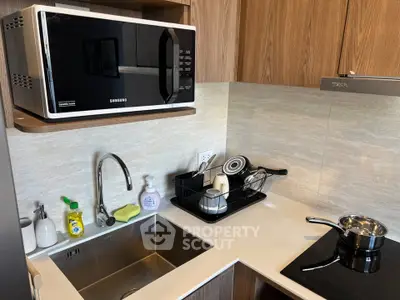Modern kitchen with microwave, sink, and sleek countertop design.