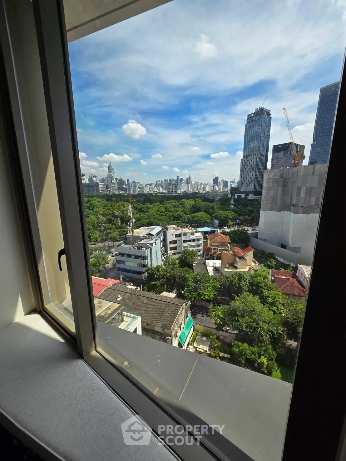Stunning cityscape view from a high-rise window showcasing urban skyline and lush greenery.