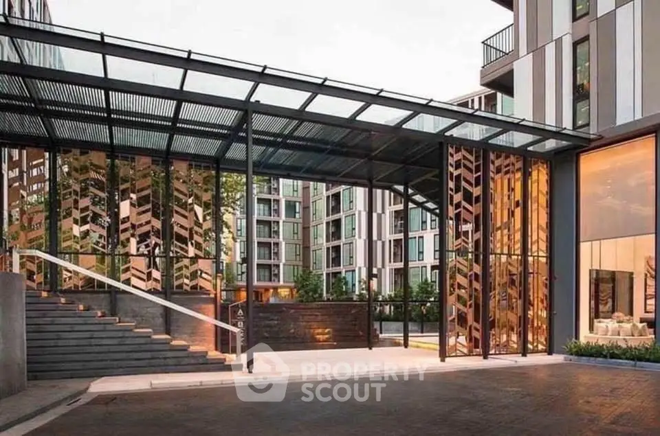 Modern apartment building entrance with glass canopy and stylish design