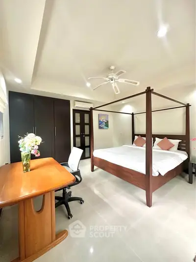 Spacious bedroom with elegant four-poster bed and modern office desk setup.