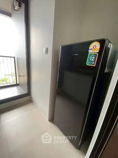Modern apartment with sleek black fridge and balcony view, perfect for urban living.