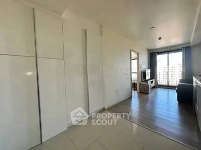 Modern apartment interior with sleek white cabinets and spacious living area with city view.