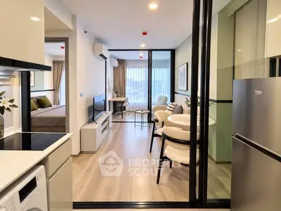 Modern open-plan apartment with sleek kitchen and cozy living area, featuring a view into the bedroom.
