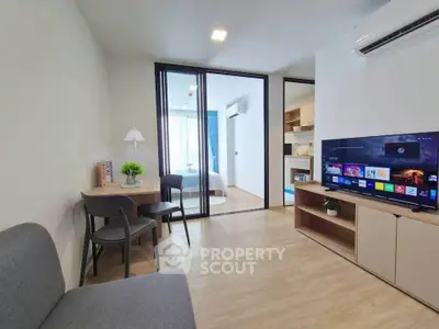 Modern living room with sleek furniture and open layout, featuring a view into a cozy bedroom.