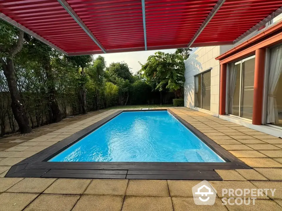 Luxurious private pool with modern red pergola and lush greenery