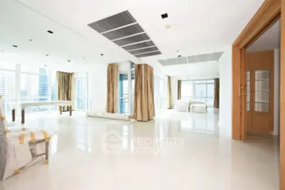 Spacious modern living room with large windows and city view, featuring elegant curtains and glossy floors.