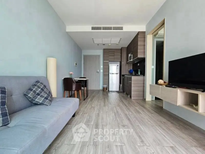 Modern living room with open kitchen, stylish decor, and wooden flooring in a contemporary apartment.