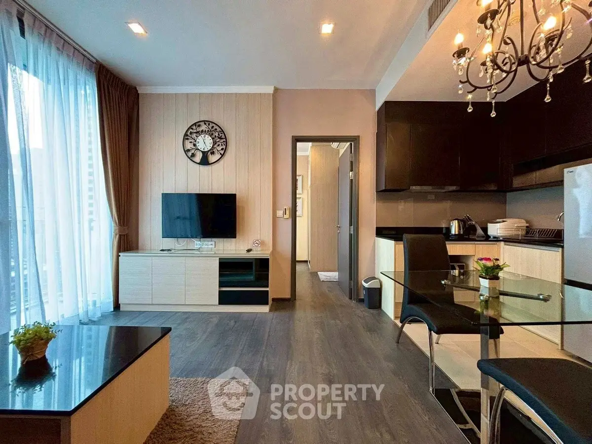 Modern living room with open kitchen, elegant decor, and natural light.