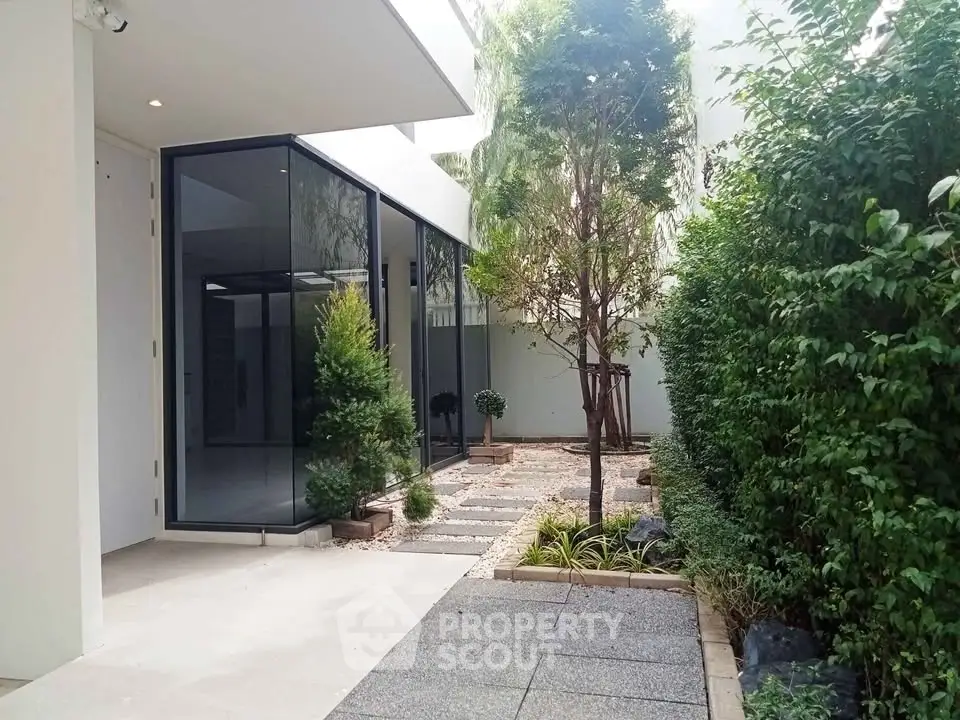 Modern garden courtyard with sleek glass walls and lush greenery