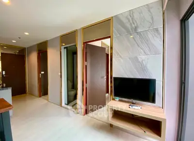 Modern apartment interior with sleek design and natural light, featuring a TV and stylish wall paneling.