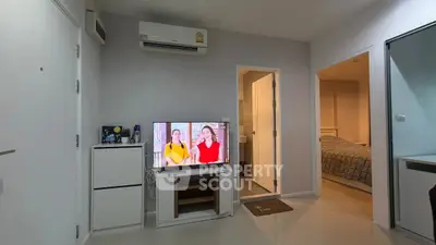 Modern living room with TV, air conditioning, and view into bedroom and bathroom.