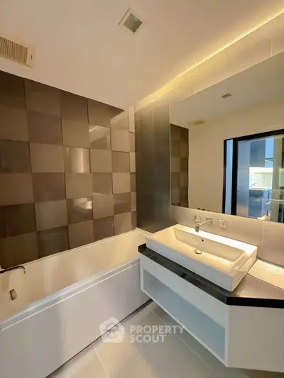 Modern bathroom with sleek design, featuring a large mirror and stylish bathtub.