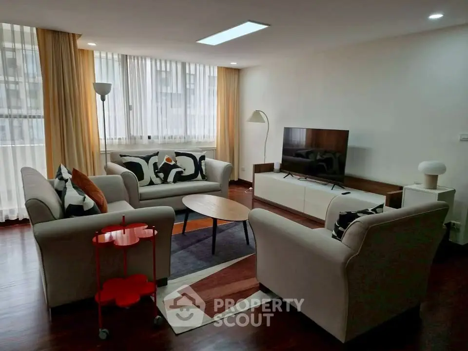 Spacious living room with modern furniture and large windows in a stylish apartment.