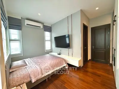 Modern bedroom with wooden flooring and wall-mounted TV