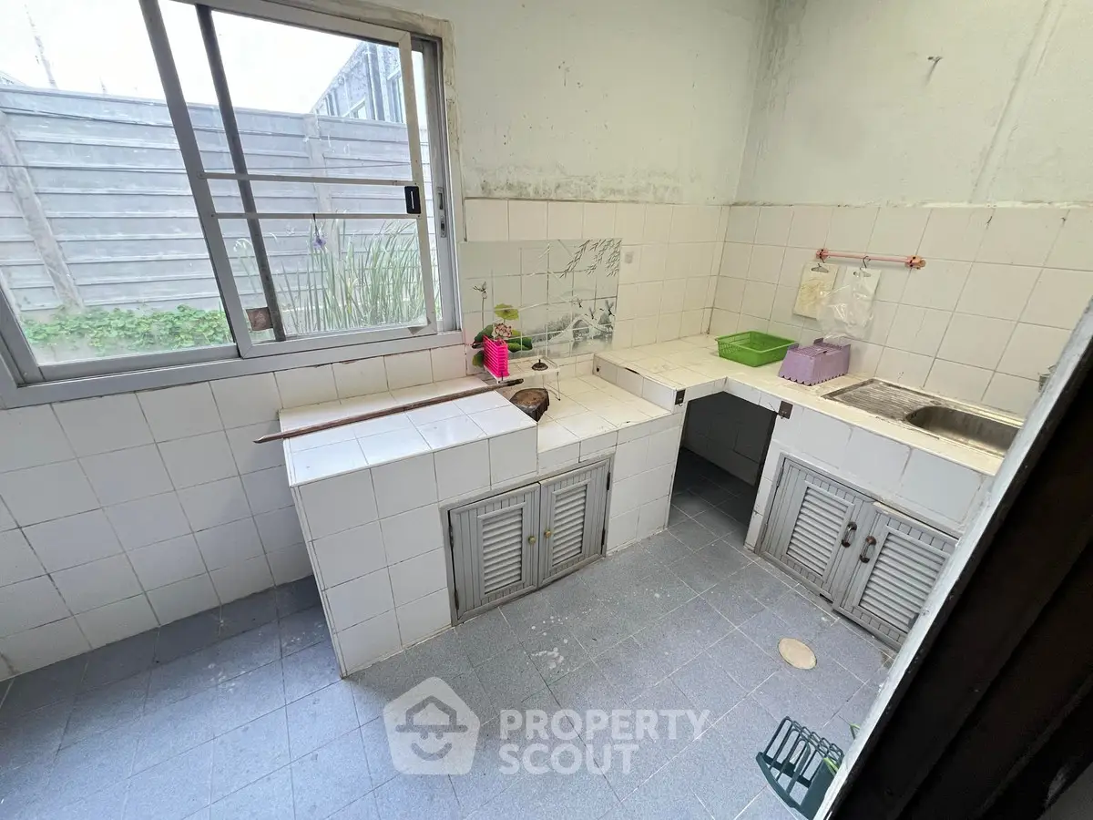 Compact kitchen with tiled countertops and window view, ideal for small spaces.