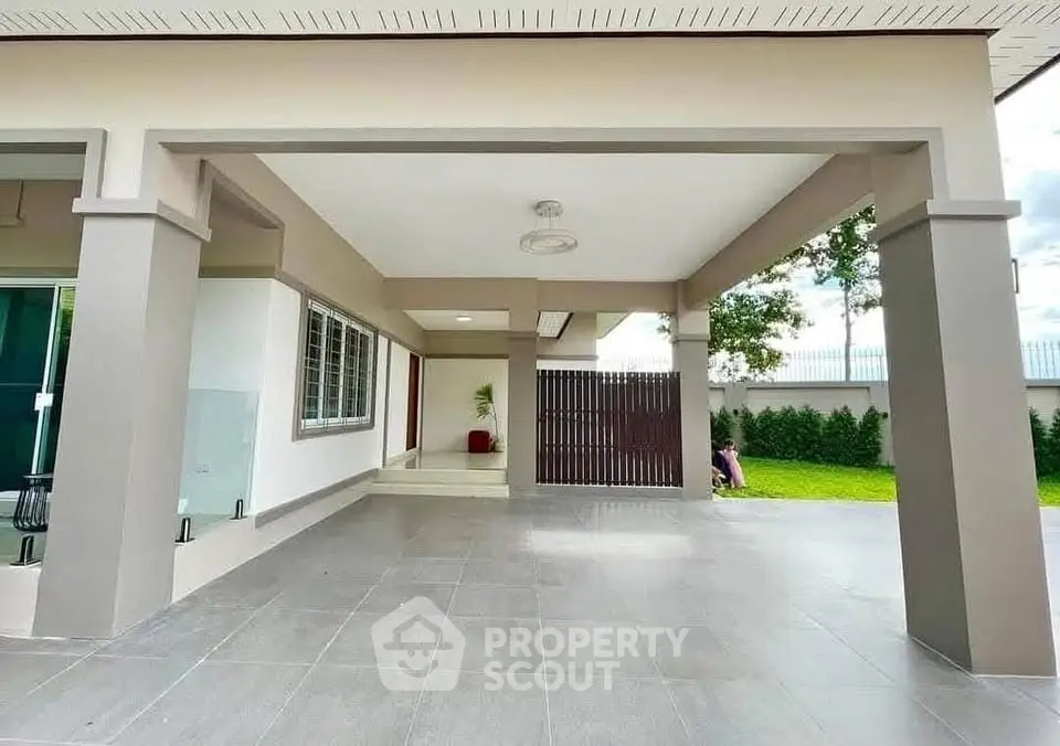 Spacious modern home entrance with covered patio and lush green garden.