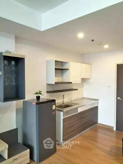 Modern compact kitchen with sleek cabinetry and wood flooring in a stylish apartment.