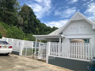 Charming white house with picket fence and lush greenery, perfect for serene living.