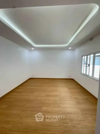 Spacious empty room with modern ceiling design and wooden flooring, perfect for customization.