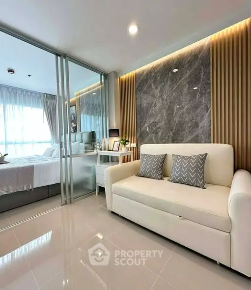 Modern living room with elegant decor and glass partition to bedroom