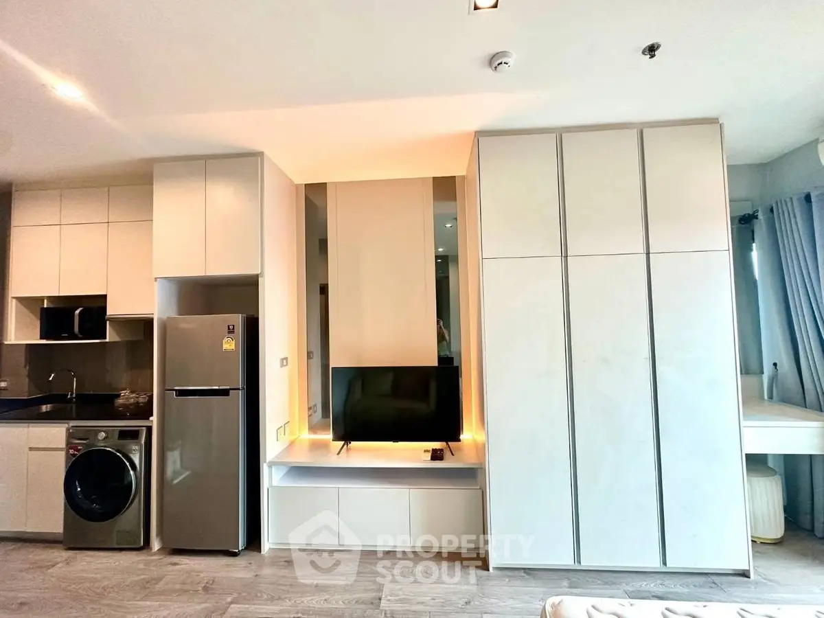Modern apartment interior with sleek kitchen and stylish living area featuring built-in storage and appliances.