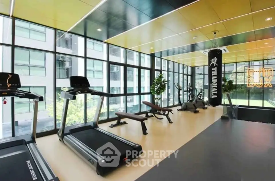 Modern gym with large windows and fitness equipment in a luxury apartment building.