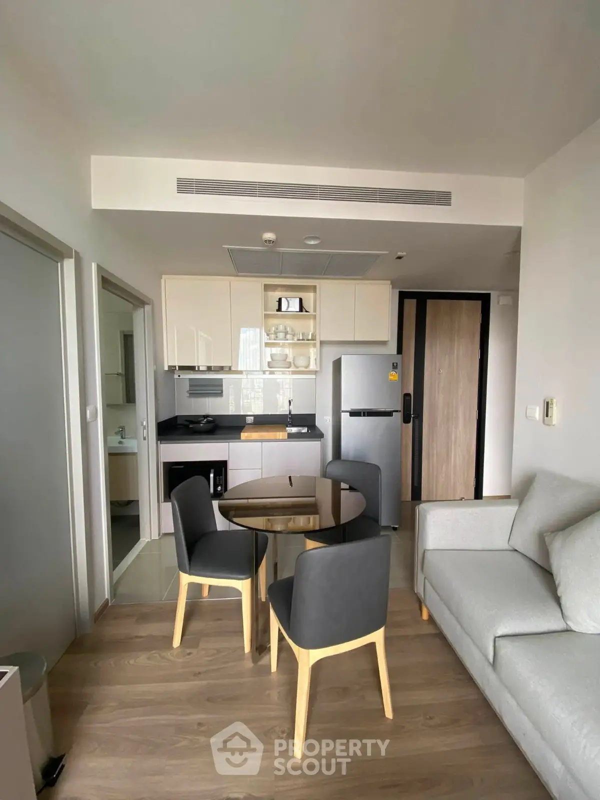 Modern apartment interior with open kitchen and cozy living area, featuring sleek furniture and contemporary design.