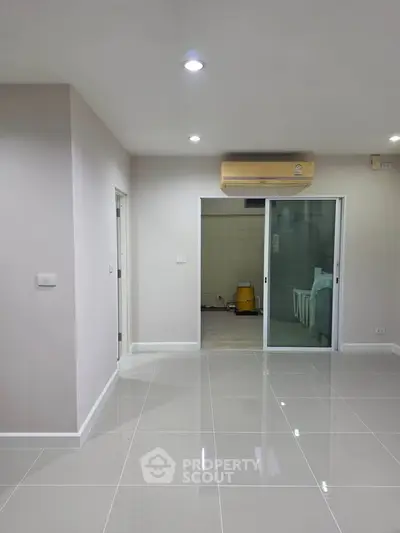 Spacious modern living room with glossy tiled floors and sliding glass doors.