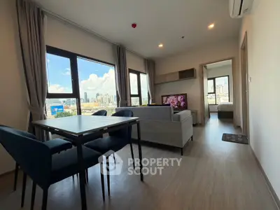Modern living room with city view, stylish furniture, and natural light in a high-rise apartment.