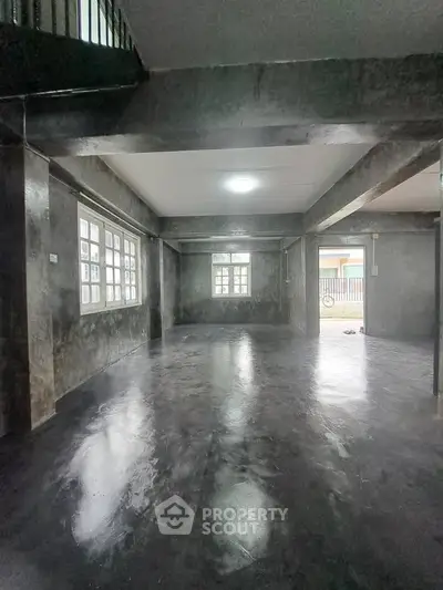 Spacious industrial-style living room with polished concrete floors and large windows.